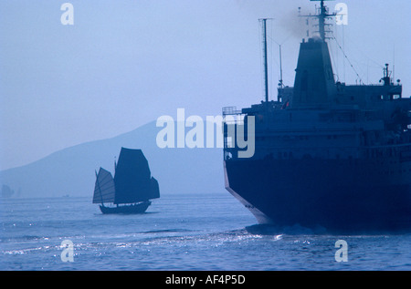 In stile tradizionale Cinese indesiderata di vela verso la fine degli anni settanta con la silhouette della vecchia nave da carico nel porto Victoria Hong Kong Cina Foto Stock