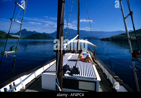 Ragazza bikini e le persone a bordo di una imbarcazione locali navigando tra le piuttosto le baie e le isole di Angra dos Reis Costa Verde del Brasile Foto Stock