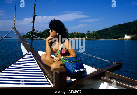 Piuttosto bikini ragazza placcati sulla prua di una barca locale navigando tra le piuttosto le baie e le isole di Angra dos Reis Costa Verde del Brasile Foto Stock
