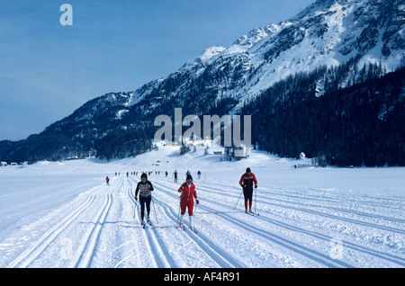 Cross country o sciatori langlauf ski in apposite piste attraverso una coperta di neve lago ghiacciato a Sils Engadina svizzera Foto Stock