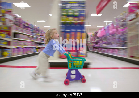 Profilo laterale di una ragazza spingendo un carrello della spesa in un supermercato Foto Stock