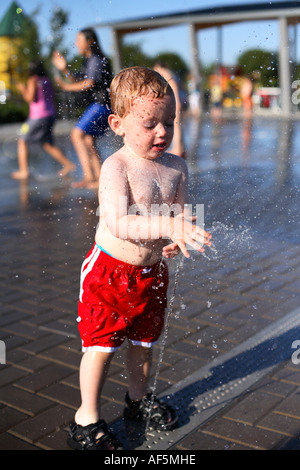 Due anni di vecchio ragazzo giocando in acqua fontana. Foto Stock