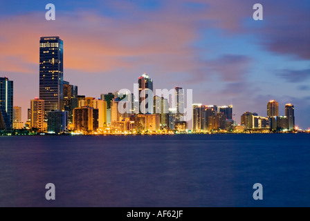 Luci brillano in highrise edifici per uffici che la linea Brickell Avenue come alba luce si riflette sulla Baia di Biscayne, Miami, Florida. Foto Stock