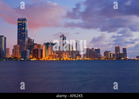 Luci brillano in highrise edifici per uffici che la linea Brickell Avenue come alba luce si riflette sulla Baia di Biscayne, Miami, Florida. Foto Stock