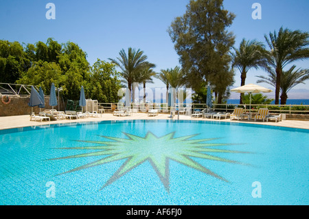 In orizzontale ampia angolazione del deserto blu brillante piscina circondata da palme tropicali al sole Foto Stock