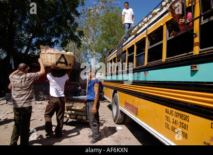 Uomo che porta un enorme cestino di meloni sulla testa per essere caricato sul bus colorato, Nicaragua Foto Stock