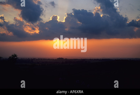 Il sole al tramonto si rompe attraverso le nuvole sopra la campagna Oxfordshire Foto Stock