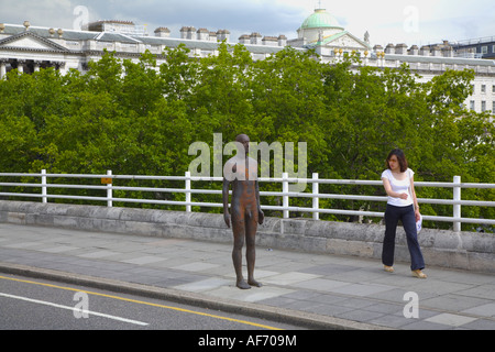 Un passante da guarda uno di Antony Gormley's statue sul ponte di Waterloo estate 2007 Foto Stock