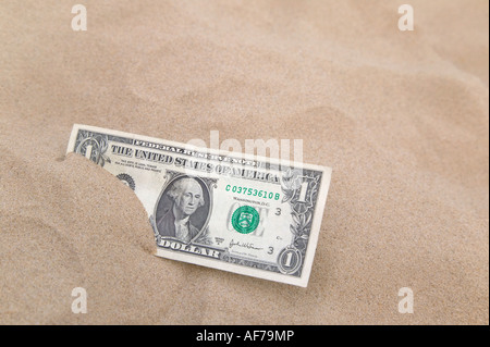 Un dollaro Usa parzialmente interrato in sabbia focus sulla nota Foto Stock