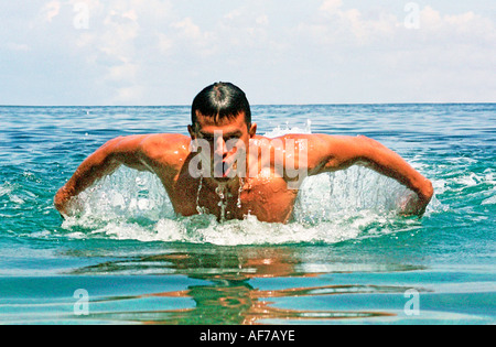 Uomo di nuoto corsa farfalla in calma il mare blu dell'acqua. Foto Stock