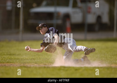 Giocatore di baseball gettando la sfera durante la caduta per lato. Foto Stock