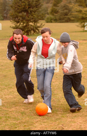 Un gruppo di ragazzi adolescenti e le ragazze a giocare a calcio in un Park Regno Unito Foto Stock