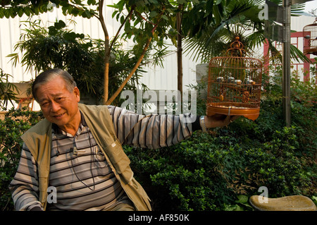 Uomo cinese con uccello in gabbia presso il Bird Garden, Mong Kok, Kowloon, Hong Kong, Cina Foto Stock