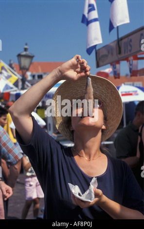 Paesi Bassi Volendam giovane donna mangiare aringa cruda nel tipico modo olandese Foto Stock