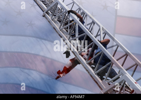 Due vigili del fuoco la visualizzazione della bandiera americana fuori una scaletta a un evento di sicurezza Foto Stock