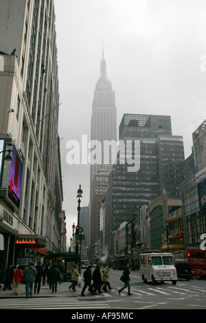 Empire State Building è avvolta nella nebbia come pedoni che attraversano crosswalk sulla 7th Ave e 34th street outside macys Foto Stock