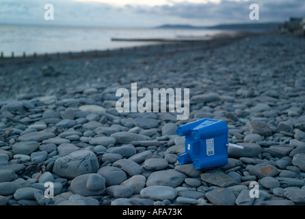 Bambini castello blu a forma di secchio di plastica abbandonata su una spiaggia di ciottoli serata estiva, alla fine delle vacanze estive Foto Stock