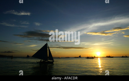 Barche a vela off di spiaggia bianca al tramonto in Boracay, Filippine. Foto Stock