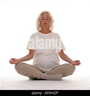 Donna incinta meditando nella posizione del loto Foto Stock