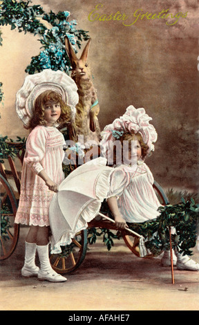 Inizio novecento auguri pasquali cartolina raffigurante due giovani ragazze spingendo un carrello. Circa 1905 U.K. Foto Stock