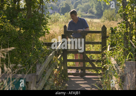 Un uomo apre una porta su Bird house prato Ambleside Cumbria su una sera d'estate Foto Stock