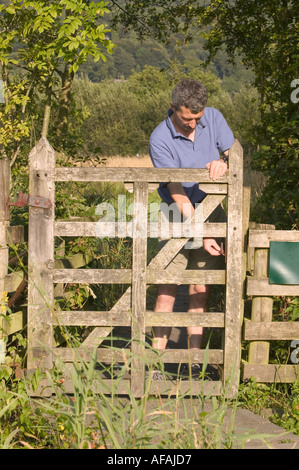 Un uomo apre un cancello in Birdhouse Prato a ricchi di specie watermeadow in Ambleside Cumbria Regno Unito Foto Stock