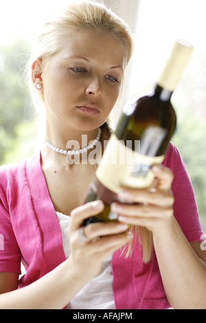 Donna che guarda la etichetta sulla bottiglia di vino Foto Stock