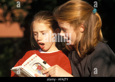 Due ragazze guardando un libro dei segreti Foto Stock