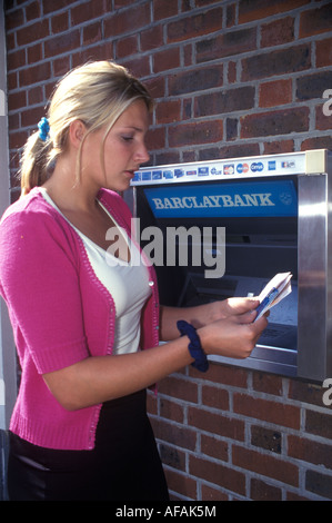 Donna di ottenere denaro da un bancomat nella parete Foto Stock