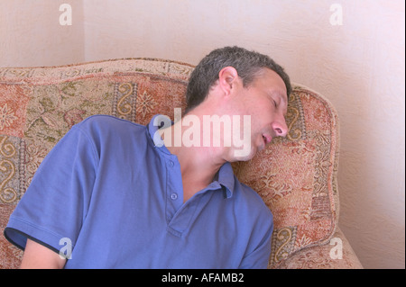 Un uomo addormentato in una poltrona Foto Stock