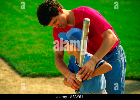 Papà coach aiuta a little leaguer lavorare sulle abilità di ovatta MR Foto Stock