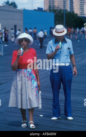 Coney Island 1980s coppia maggiore marito moglie anziani che bevono una lattina di 7 in su usando un casual di paglia smart 1981 Brooklyn, New York City USA HOMER SYKES Foto Stock