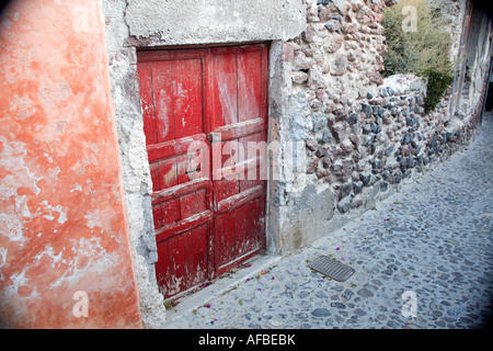 Vecchio rosso porte in caduta verso il basso la parete Foto Stock