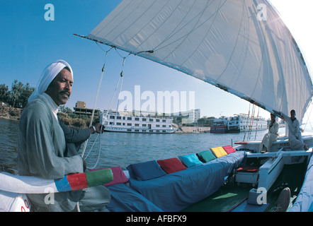 Marinaio egiziano al timone della sua feluca sul fiume Nilo a Luxor Egitto Foto Stock