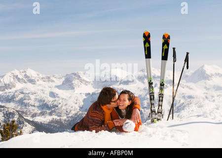 Coppia giacendo in neve, flirtare Foto Stock
