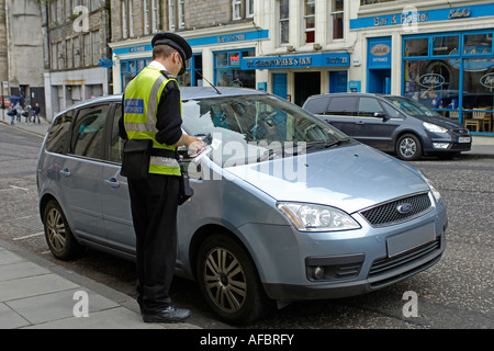 Vigile Auto Attendant di scrivere i ticket per gli automobilisti auto parcheggiata Flourescant giacca gilet misuratore a mano Foto Stock