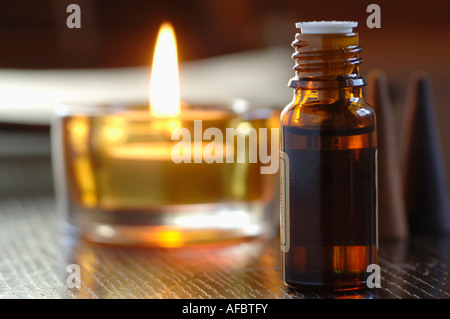 Bottiglia di olio profumato, accanto a una delle tealight, close-up Foto Stock