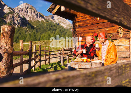Giovane seduto di fronte a capanna alpina Foto Stock