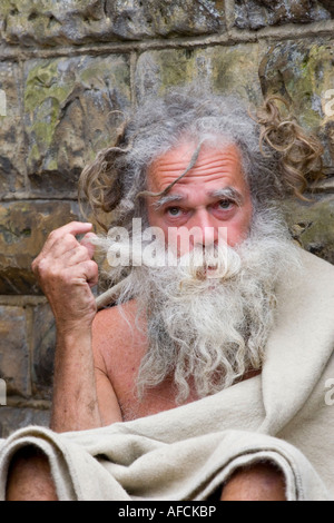 Senzatetto uomo gioca con la sua barba Foto Stock