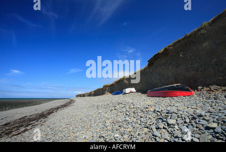 Rosso, barca capovolta sulla spiaggia Llanon, Galles. Foto Stock