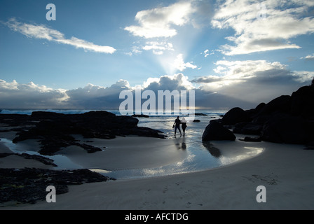 Coppia in una romantica alba passeggiata sulla spiaggia a poco baia sulla costa d'Oro in Australia Foto Stock