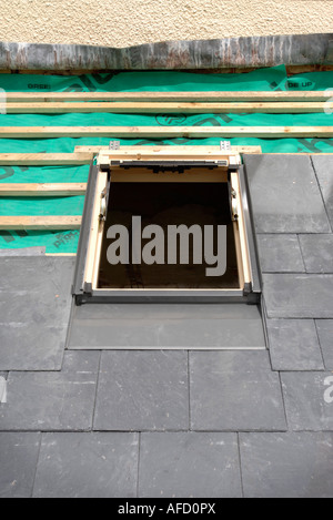 Montaggio di una finestra velux su un tetto di ardesia in costruzione che mostra la copertura traspirante feltro con bastoni di legno Foto Stock