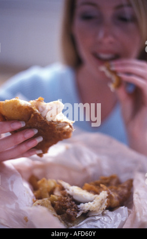 Donna che mangia pesce e patatine fritte Foto Stock