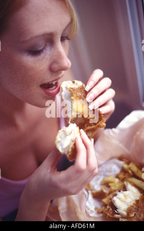 Donna che mangia pesce e patatine fritte Foto Stock