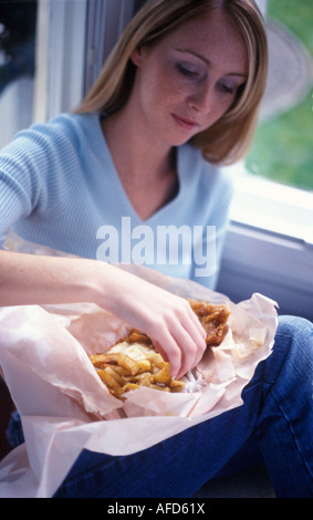 Donna che mangia pesce e patatine fritte Foto Stock