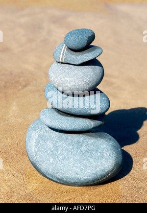 Pila di pietra grigia in equilibrio su una spiaggia di sabbia Foto Stock