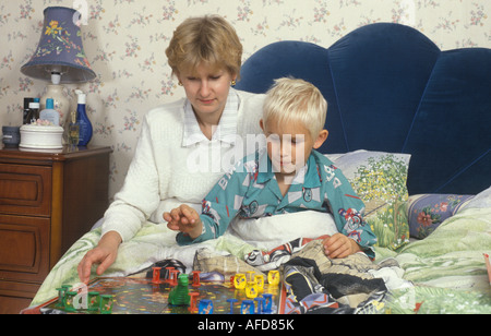 Bambino malato a letto con la madre la riproduzione di un gioco con lui Foto Stock
