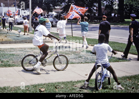 CAROLINA DEL SUD ROCK HILL Nero ragazzi su biciclette guarda come membri del Ku Klux Klan parade attraverso una piccola città del Sud Foto Stock