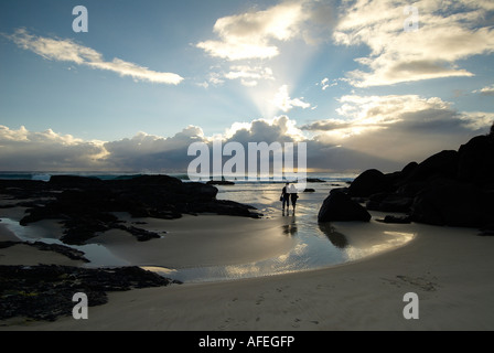 Coppia in una romantica alba passeggiata sulla spiaggia a poco baia sulla costa d'Oro in Australia Foto Stock