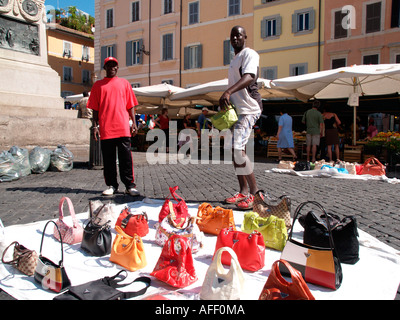 I lavoratori migranti provenienti dal Nord Africa vendita di borsette in Campo dei Fiori Roma Foto Stock